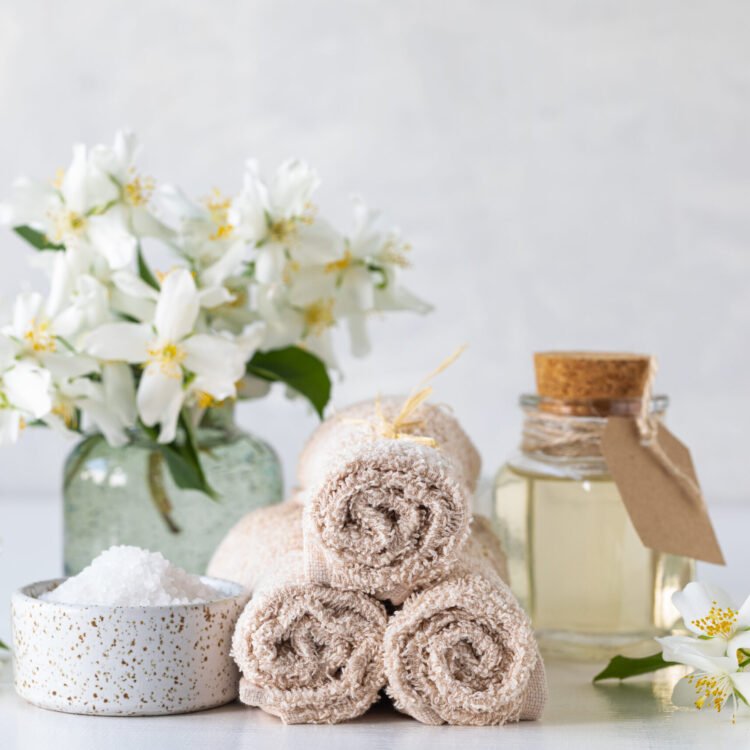 spa concept of jasmine oil, with bath salt and flowers on a white background. spa and wellness still life. copy space.
